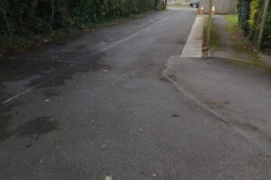 Faded car park markings on worn tarmac before re-lining