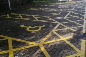 Yellow disabled parking bays with hatching on block paving