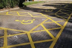 Disabled bay wheelchair symbols and yellow hatching on block paving