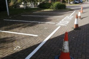 Visitor parking bay markings with traffic cones on block paving