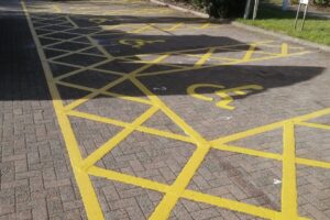 Yellow hatched disabled bay markings on a block paved car park