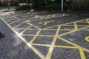 White and yellow hatched disabled bays on a block paved car park