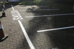 Freshly painted white bay lines and lettering on block paving