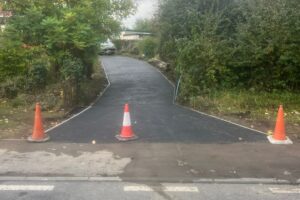 Long tarmac drive freshly laid with cones along the edge