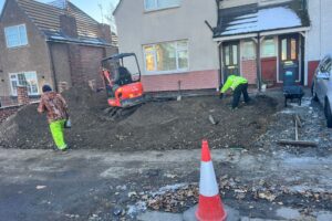 Mini digger excavating a front driveway for block paving