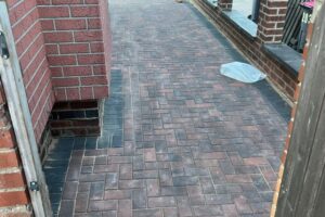 Newly laid block paving driveway beside a brick wall