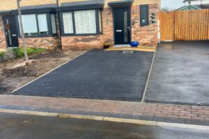 Newly resurfaced tarmac driveway in front of a brick house